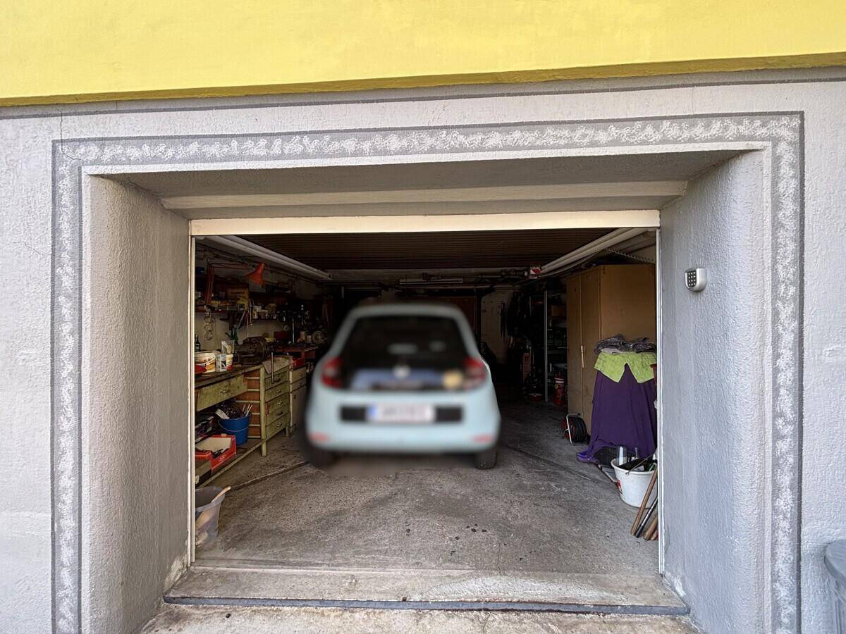 Garage mit einem geparkten Kleinwagen und Stauraum für Werkzeuge.