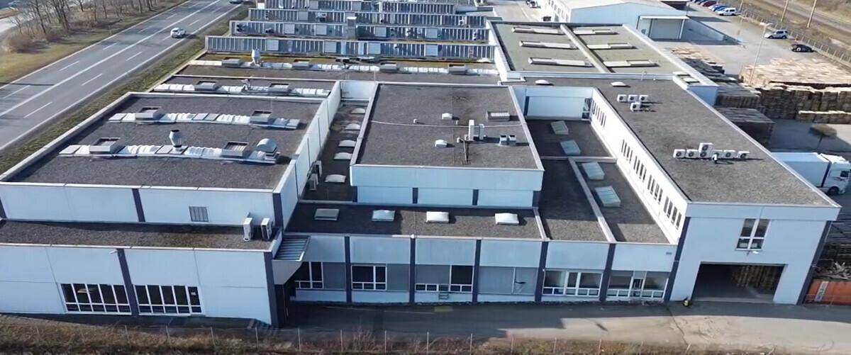 Übersicht des Gewerbegebäudes mit mehreren Flachdächern und großen Fensterfronten.