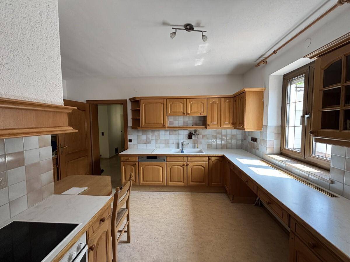 Küche im Landhausstil mit hellen Holzschränken, Arbeitsplatten und gefliestem Spritzschutz.