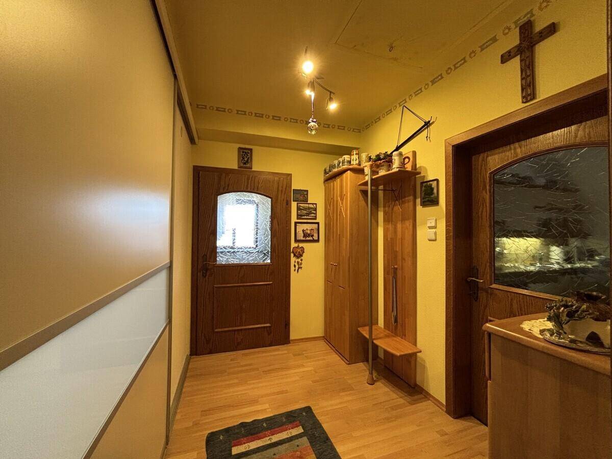 Eingangsbereich mit Holzboden, Garderobe und traditionellen Holztüren.