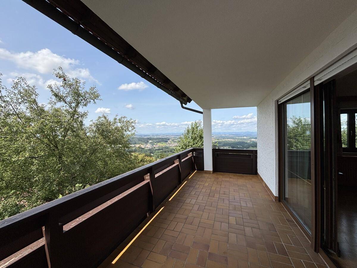 Geräumiger Balkon mit Fliesenboden und Holzgeländer, bietet einen weiten Panoramablick über die Landschaft.