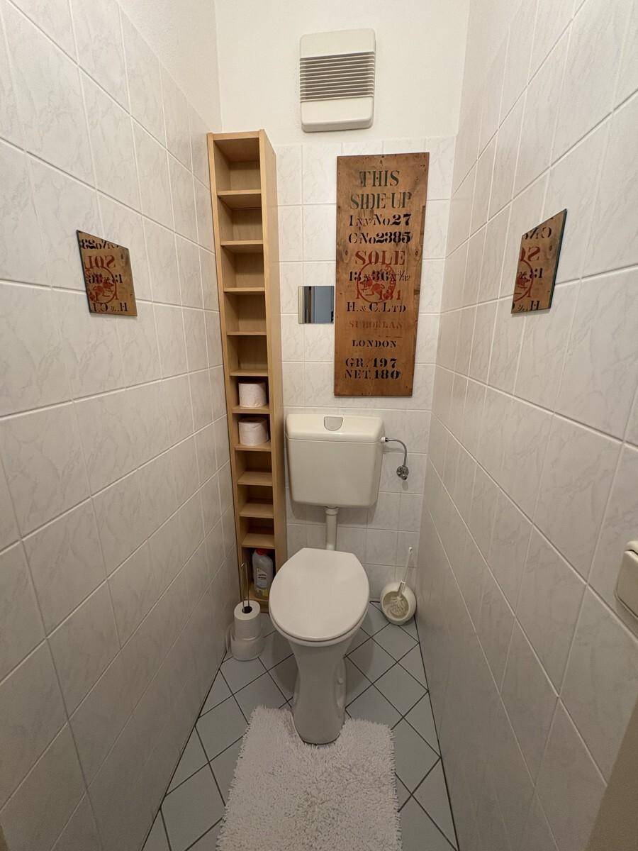Separates WC mit weißen Fliesen und Toilette, sauber und funktional.