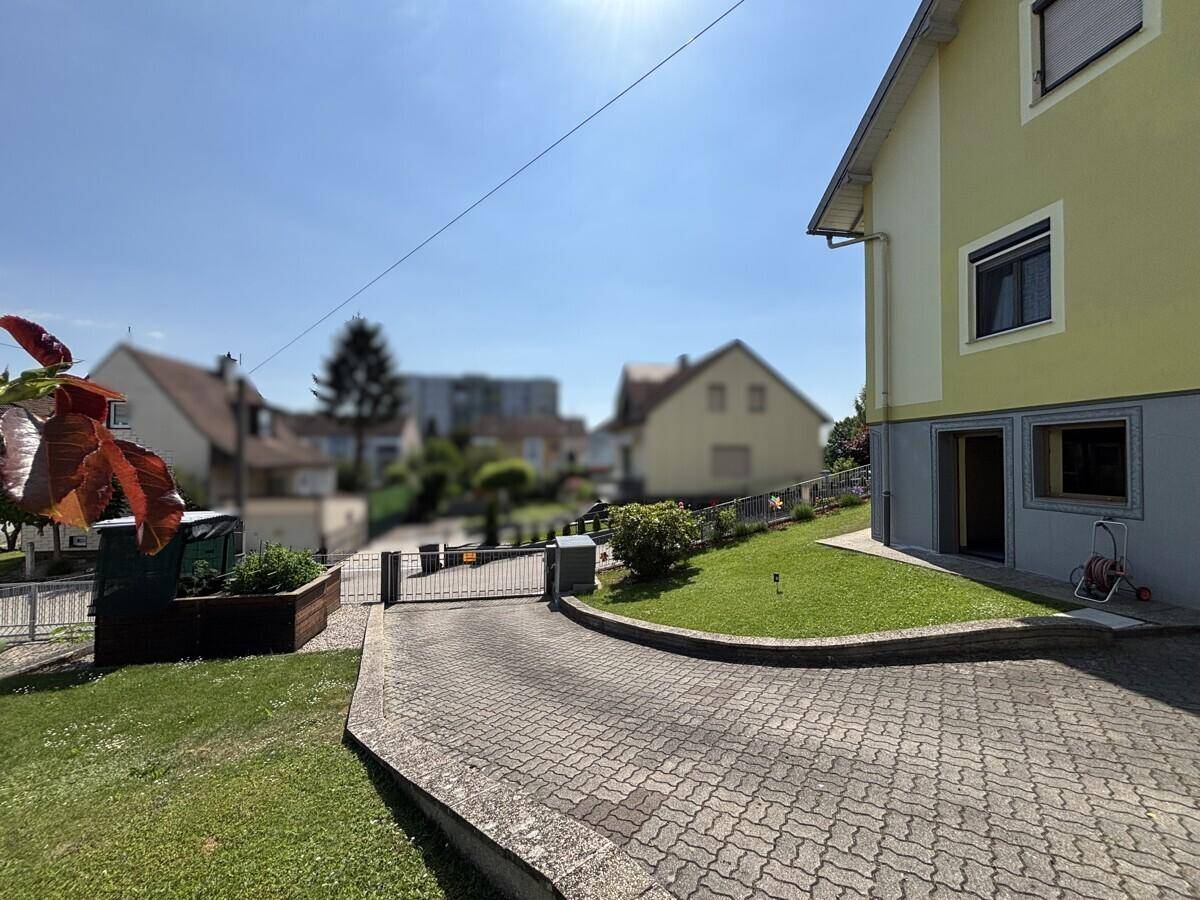 Zufahrt zum Haus mit gepflastertem Weg und grünem Vorgarten.