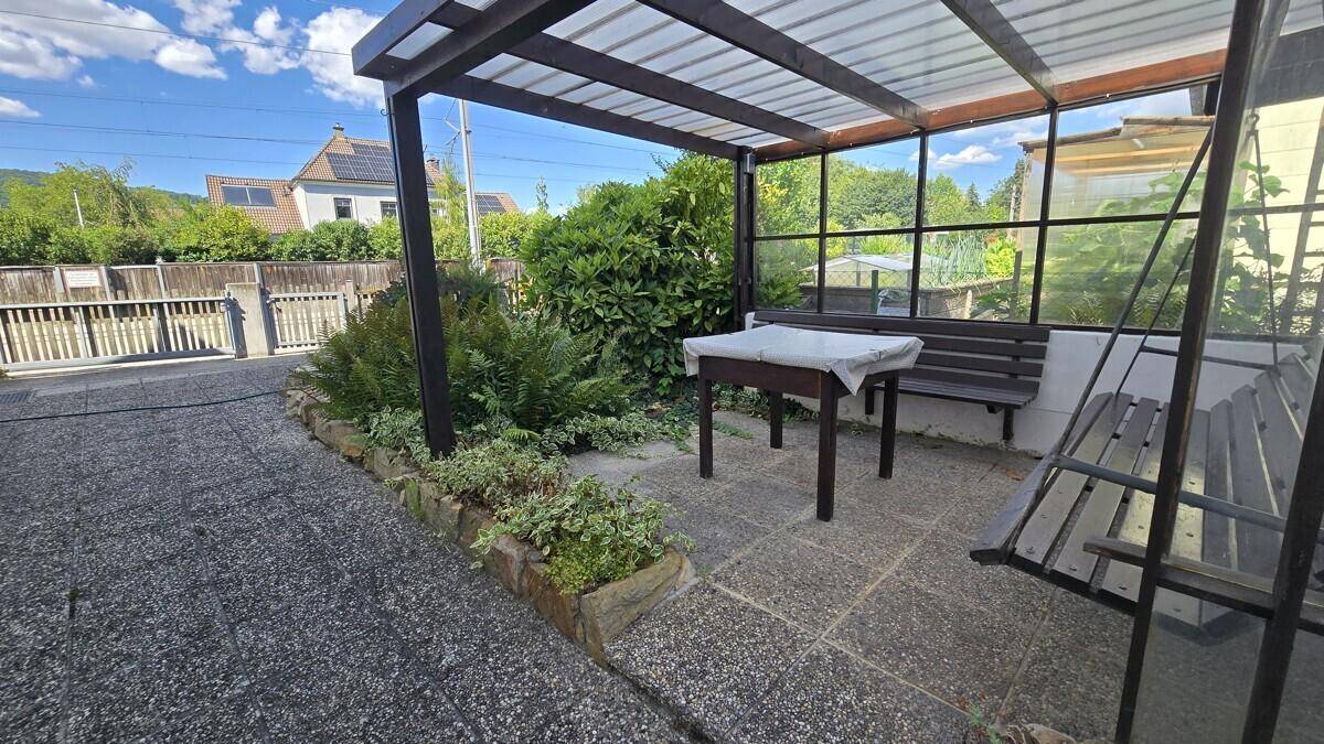 Gemütliche überdachte Terrasse mit Schaukelbank und Tisch, ideal für entspannte Stunden.