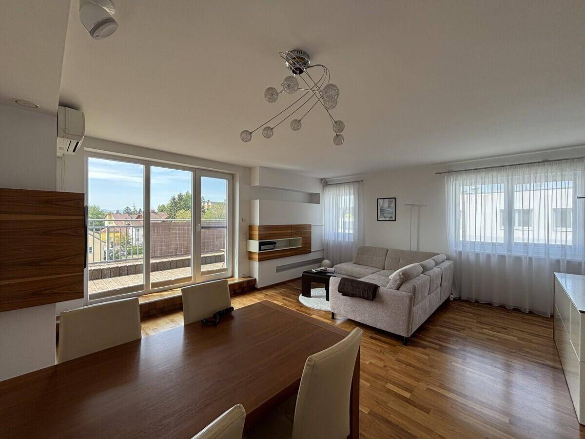 Heller Wohn-Essbereich mit Esstisch, Sofa und großen Fenstern zur Terrasse.