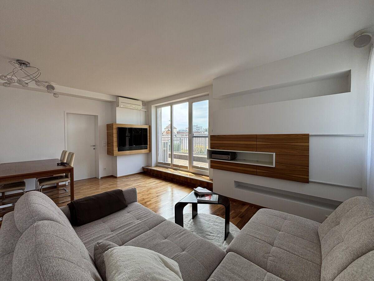 Gemütlicher Wohnbereich mit Sofa, Holzboden und Zugang zur Terrasse.
