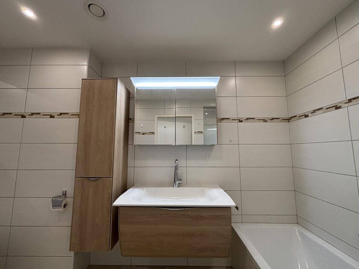 Modernes Badezimmer mit Badewanne, Waschtisch und Spiegelschrank.