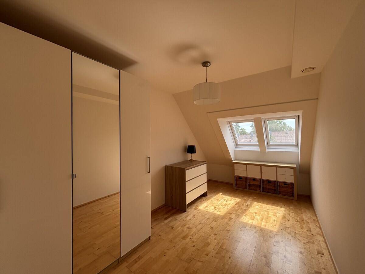 Helles Schlafzimmer mit Dachschrägen, Holzboden und Dachfenstern.