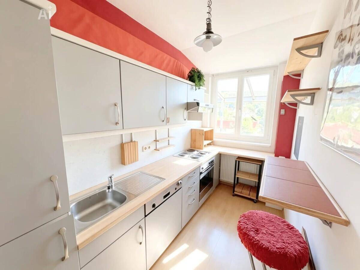 Funktionale Küche mit grauen Schränken, Holzarbeitsplatte und roter Akzentwand.
