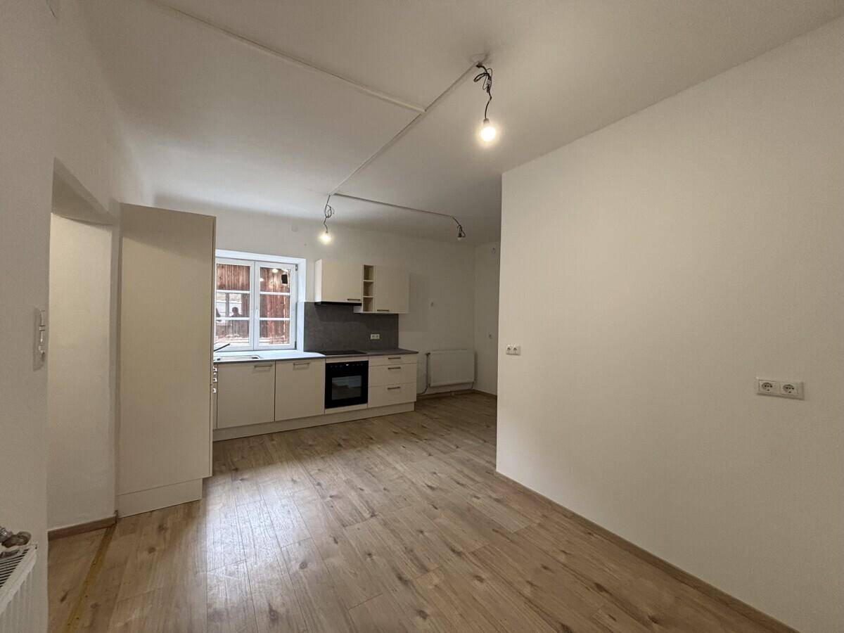 Geräumiger Bereich mit neuer Küche im Hintergrund und viel Platz für einen Essbereich.