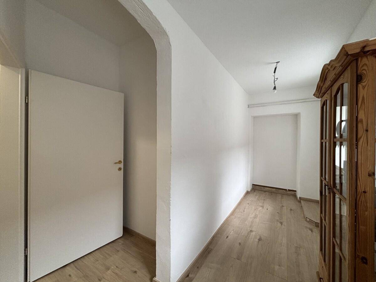 Heller Flur mit Laminatboden, einem Bogen und einem traditionellen Holzschrank.