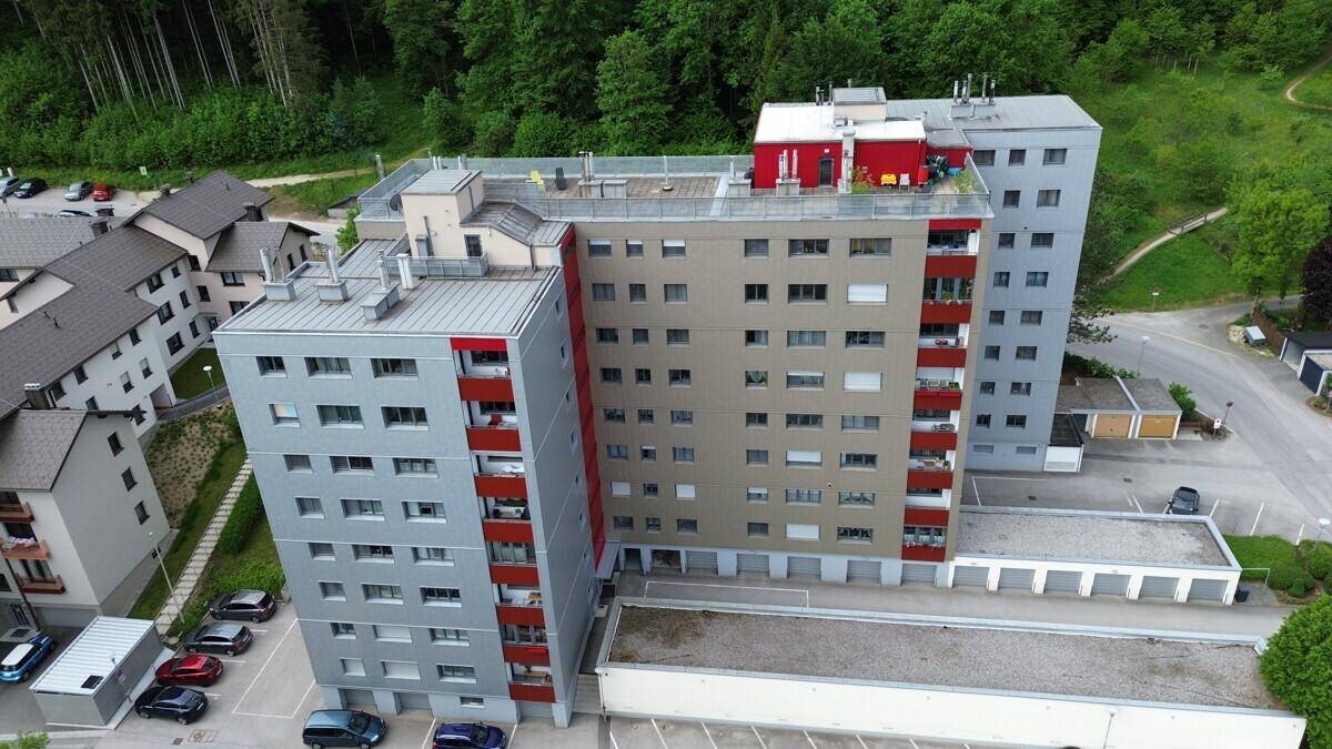 Luftaufnahme eines modernen Mehrfamilienhauses mit mehreren Etagen und umliegender Natur.