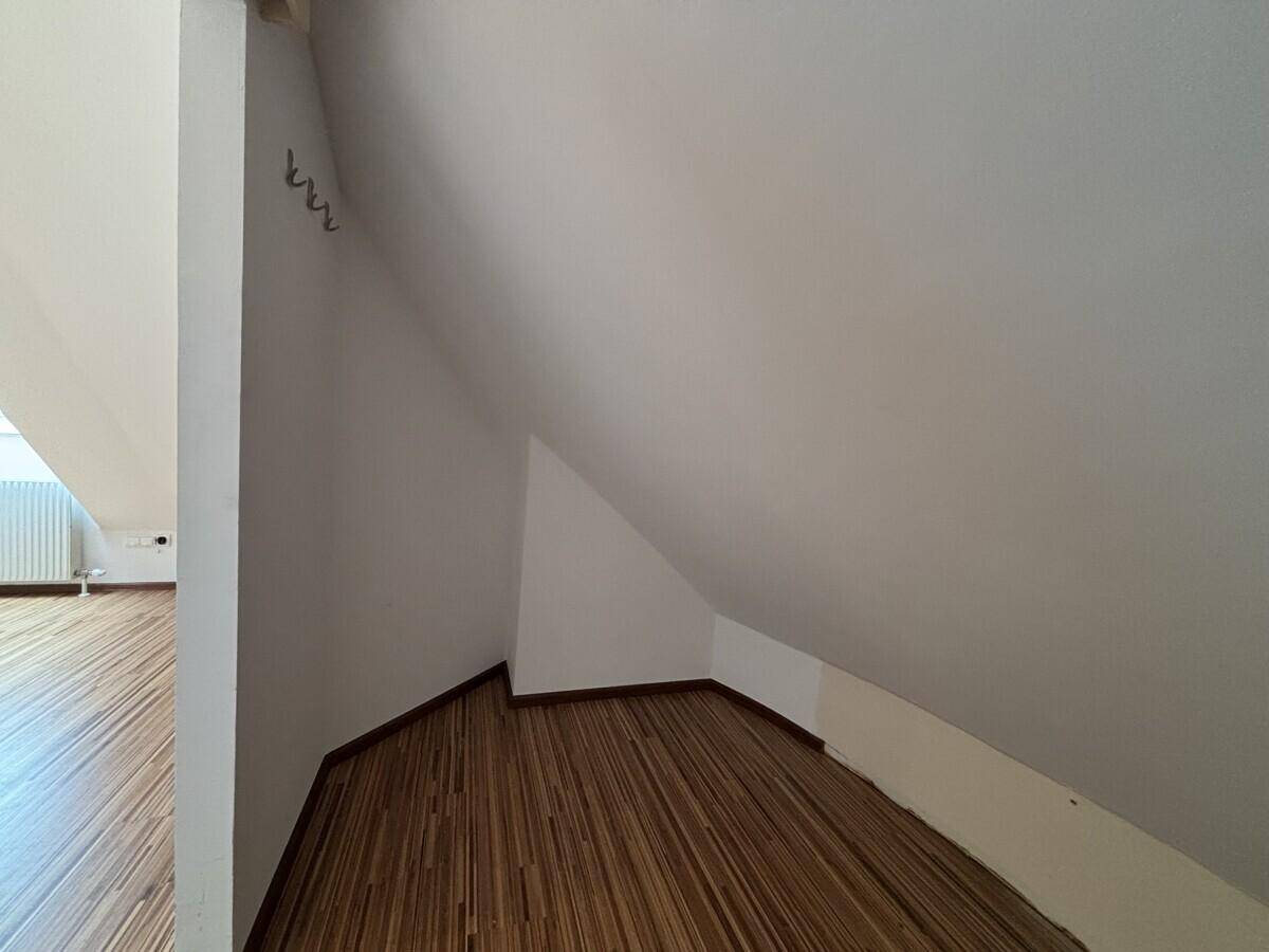 Kleiner Abstellraum im Dachgeschoss mit Holzfußboden und schrägen Wänden.