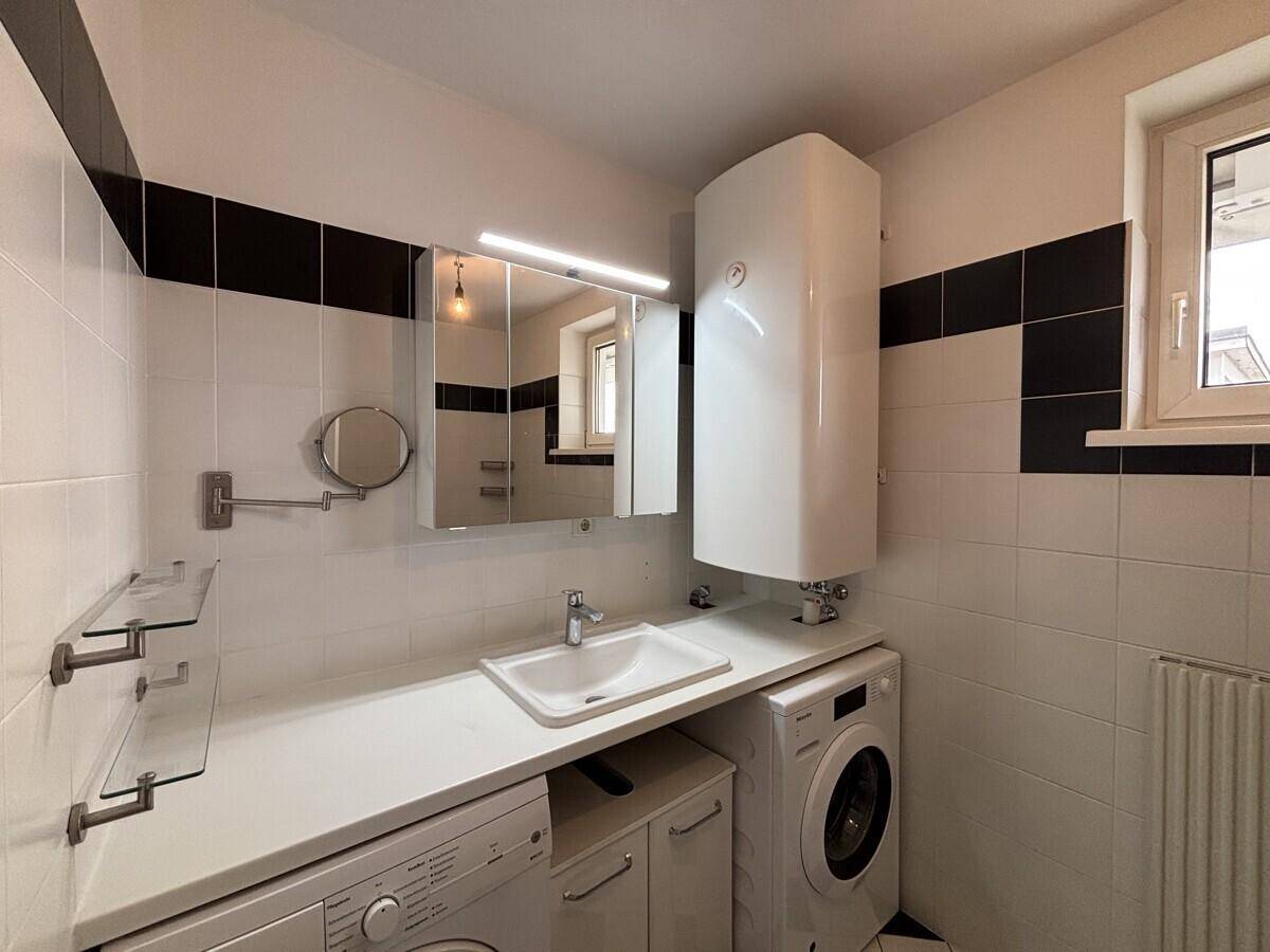 Badezimmer mit Waschbecken, Waschmaschine, Trockner und Warmwasserboiler.