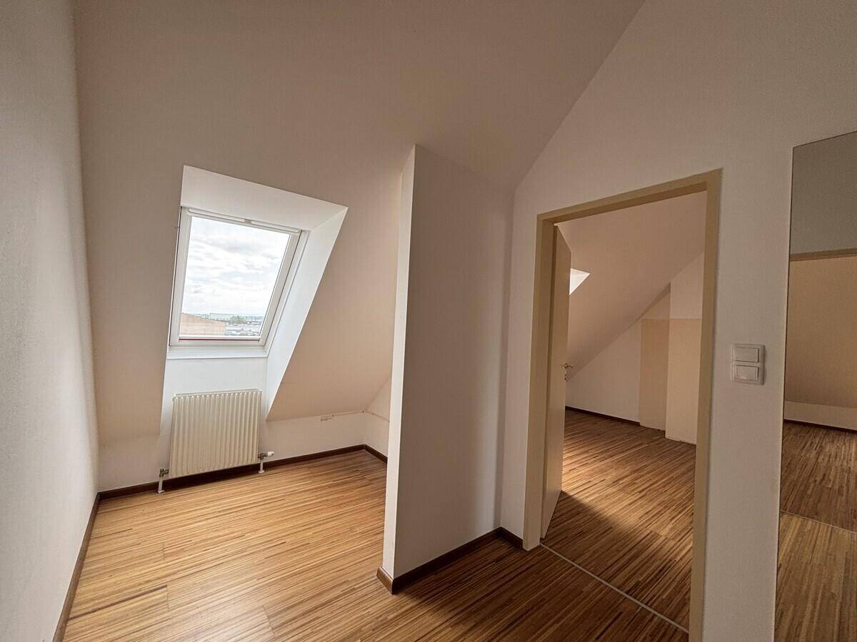 Helles Dachgeschosszimmer mit Holzfußboden und Dachfenster.