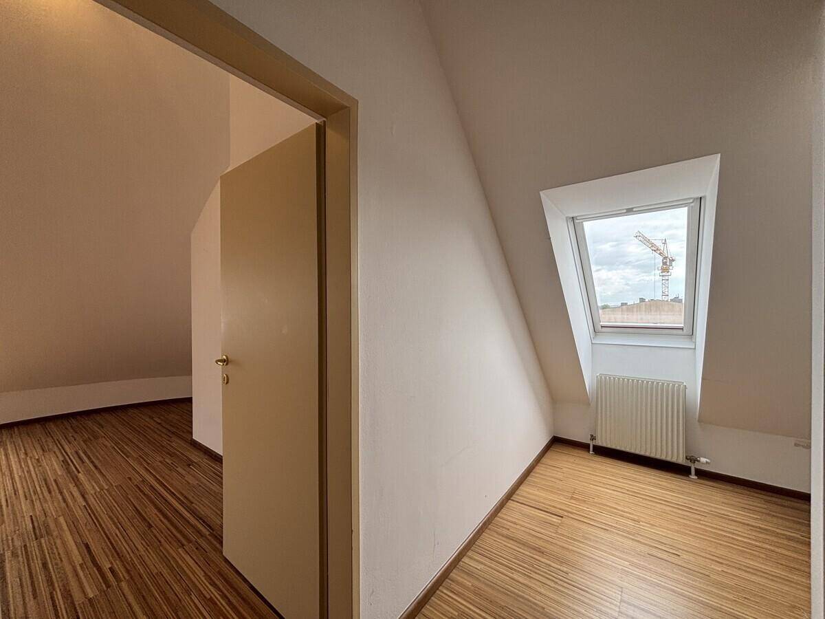 Dachgeschosszimmer mit Holzfußboden, Dachfenster und schrägen Wänden.