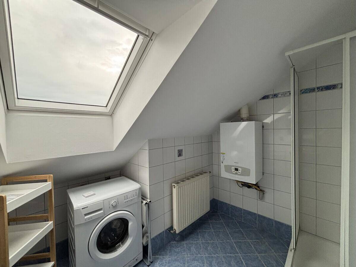 Funktionales Badezimmer mit Waschmaschine, Heizung, Gastherme und Duschkabine.