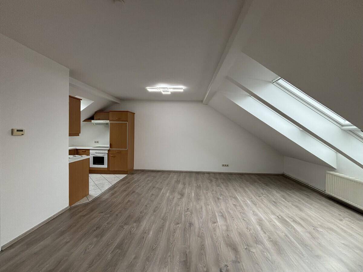 Offener Wohnbereich mit Laminatboden, Dachschrägen und einer funktionalen Einbauküche.