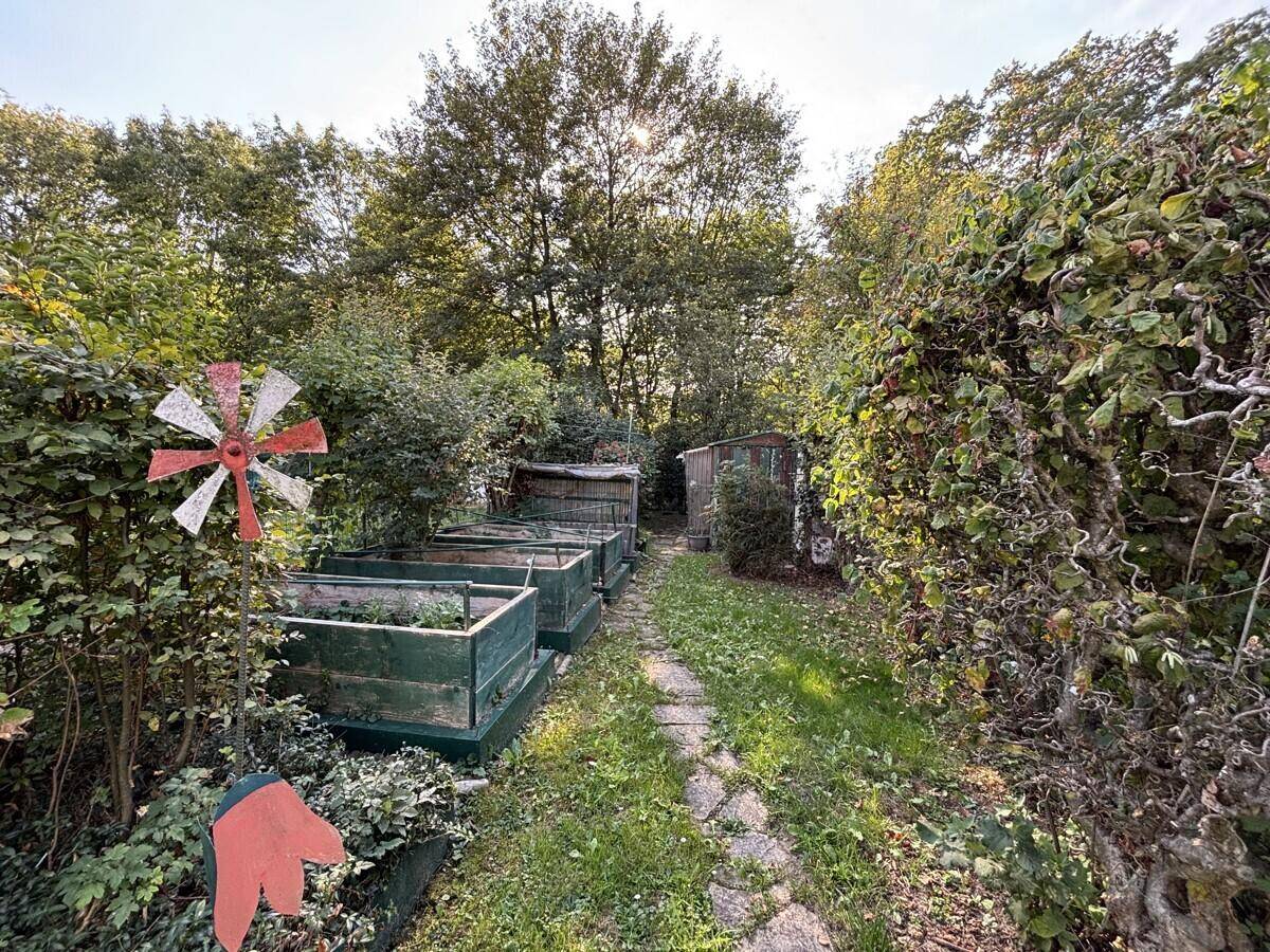 Nutzgartenbereich mit Hochbeeten und üppigem Grün, ideal für den Anbau von Gemüse und Kräutern.