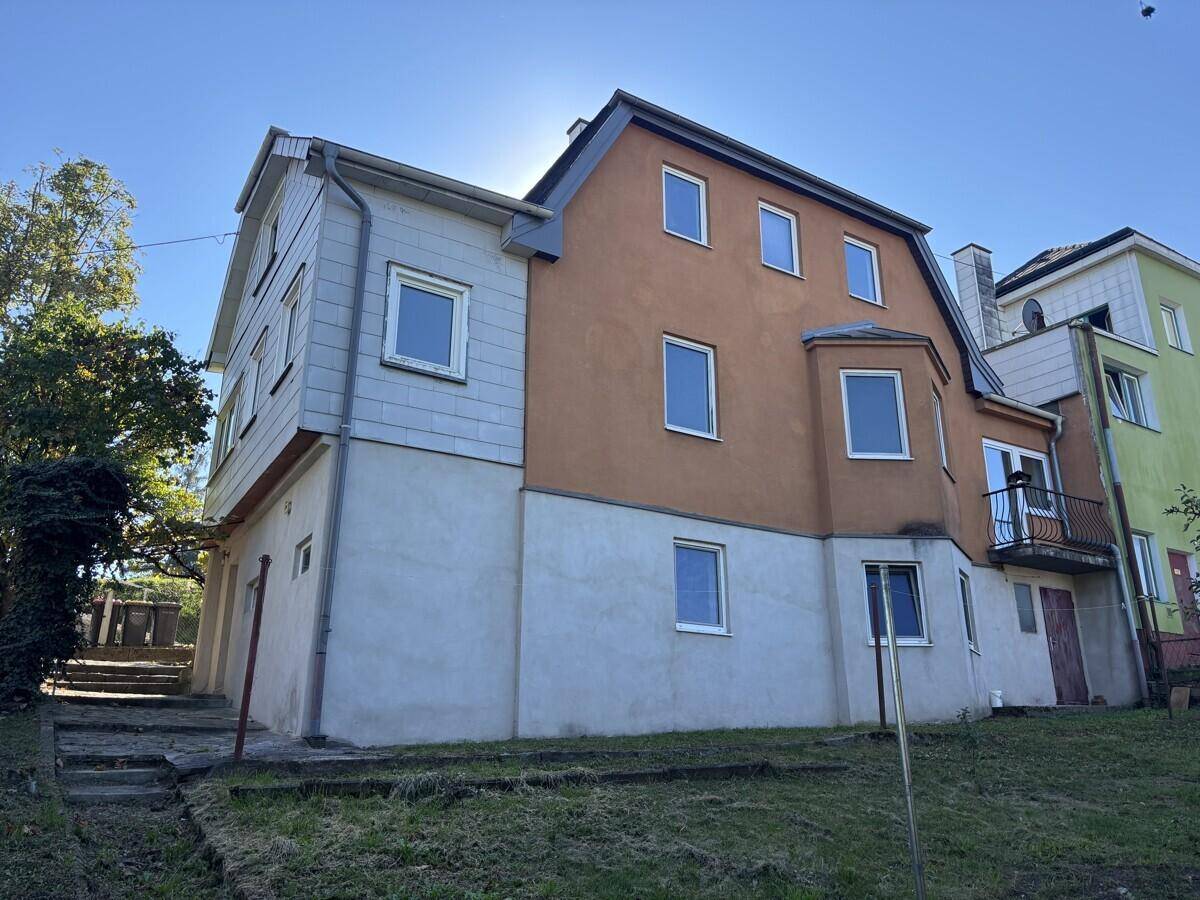 Rückansicht eines mehrstöckigen Hauses mit verschiedenen Fenstern und einem kleinen Balkon.