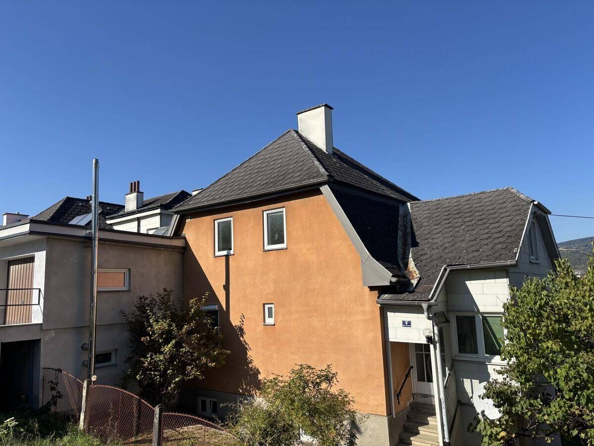 Seitenansicht eines Wohnhauses mit Garage und Eingangsbereich unter klarem, blauem Himmel.