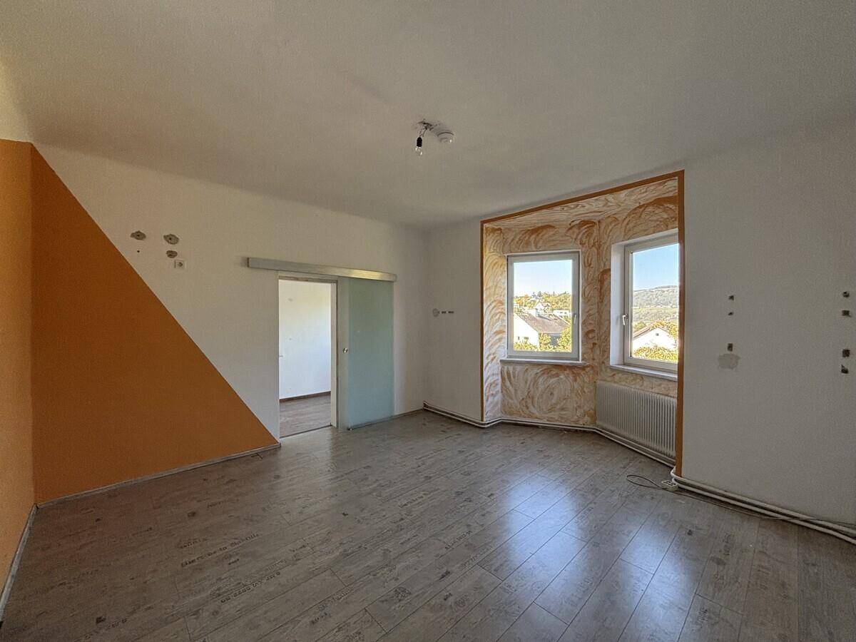 Geräumiges Zimmer mit Laminatboden, hellen Wänden und einem Erkerfenster.
