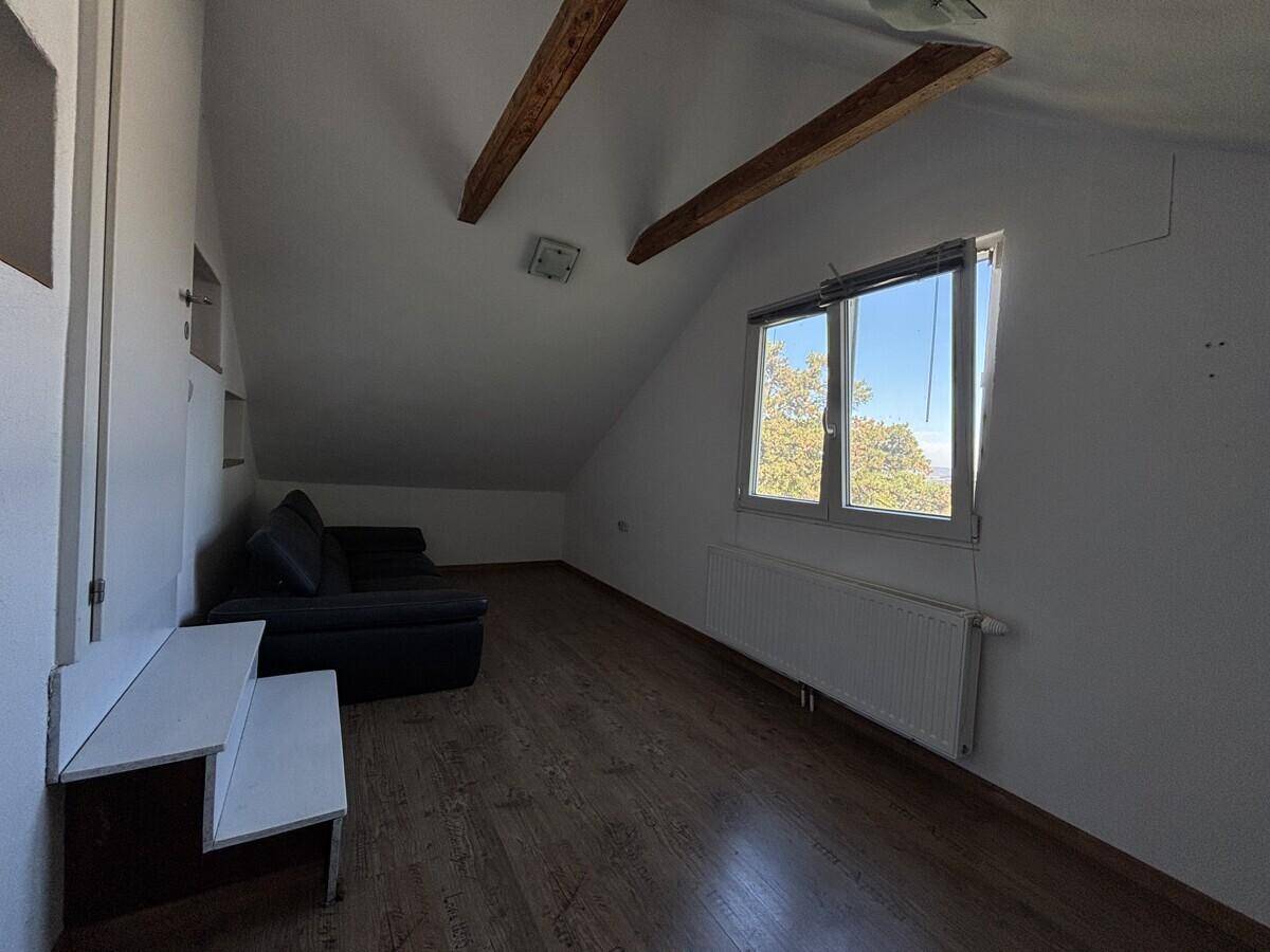 Gemütlicher Dachbodenraum mit Holzbalken, schrägen Wänden und einem Sofa.