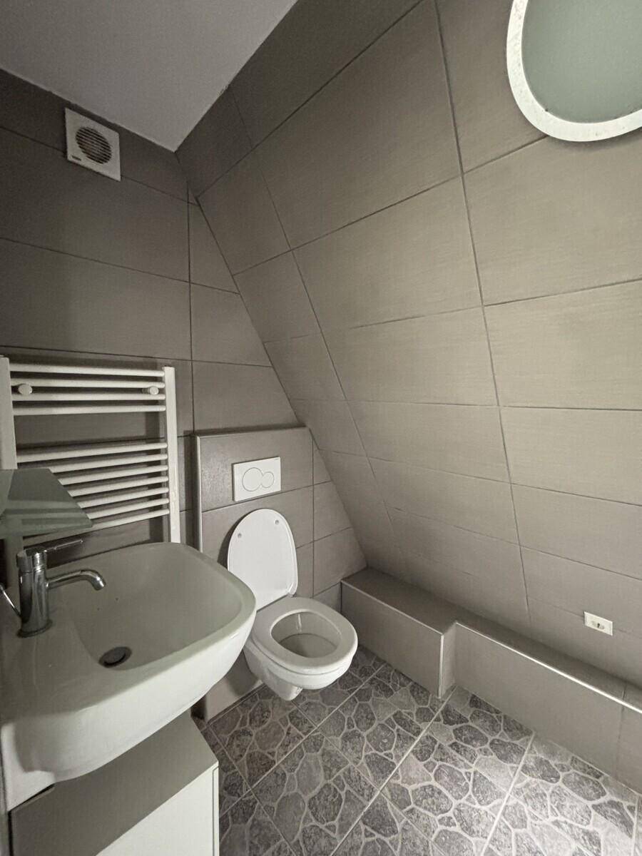 Badezimmer im Dachgeschoss mit WC, Waschbecken, beheiztem Handtuchhalter und schräger Decke.