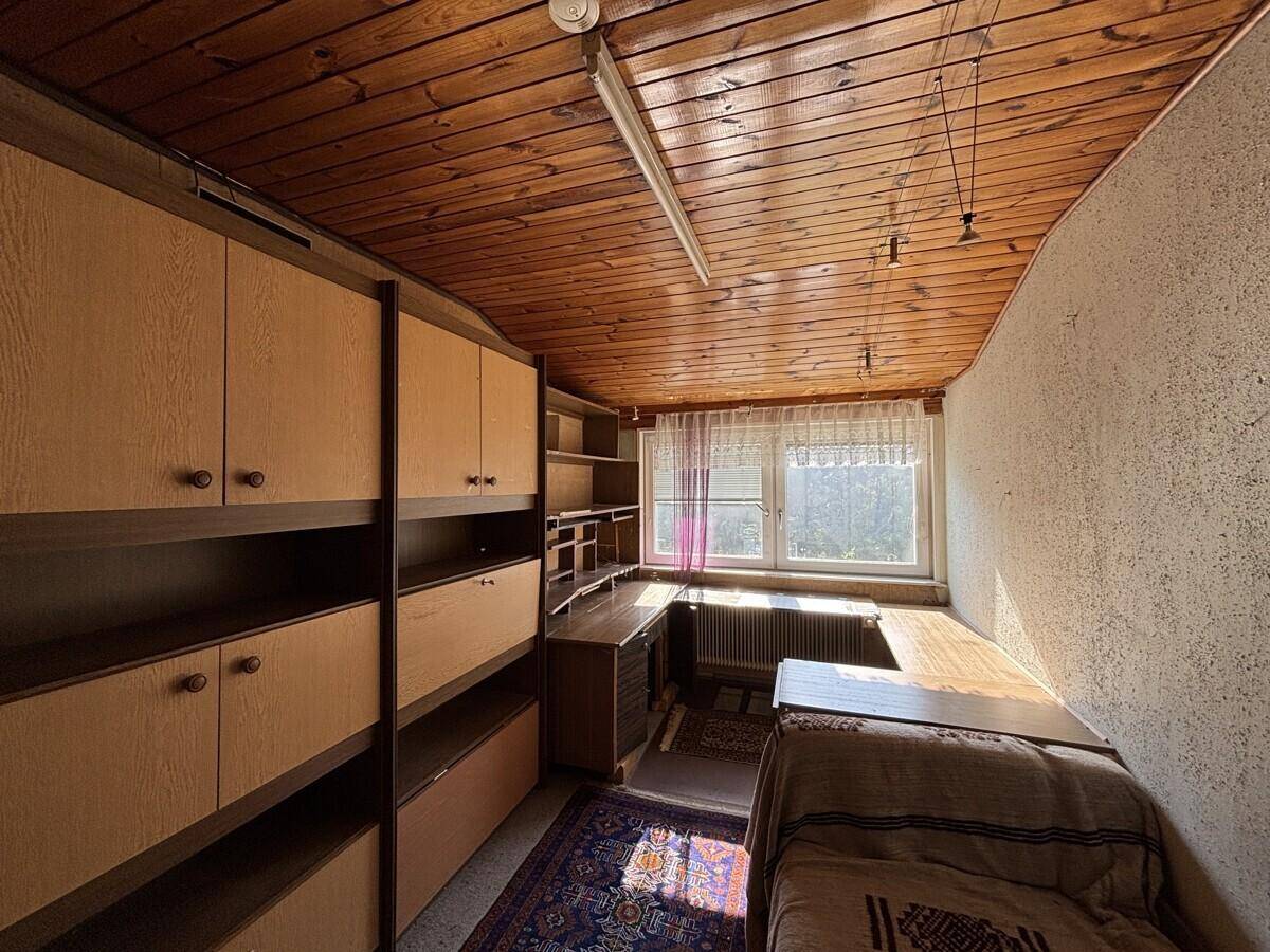 Praktisches Arbeitszimmer mit viel Stauraum durch Einbauschränke und Holzdecke, hell und funktional gestaltet.