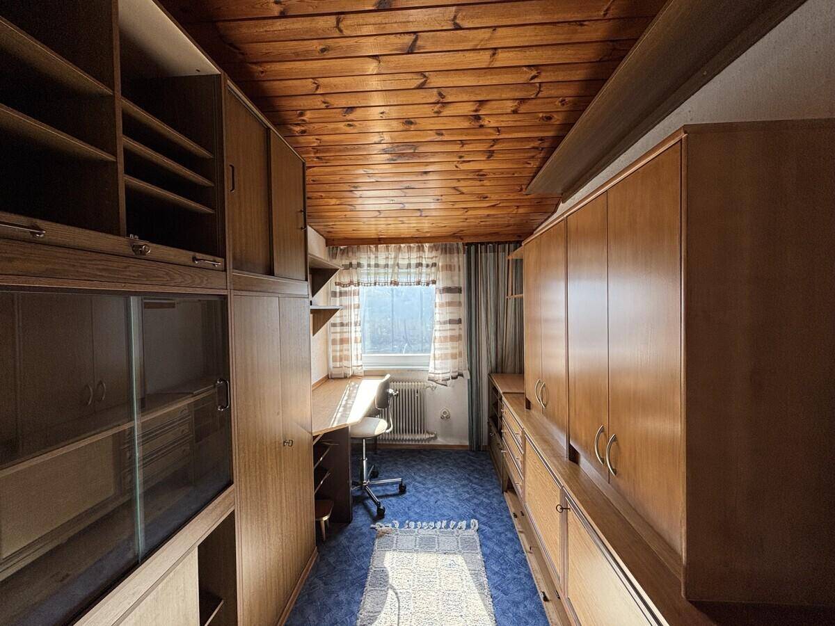 Funktionales Arbeitszimmer mit Holzdecke, Einbauschränken und Schreibtisch am Fenster, ideal für Home-Office.