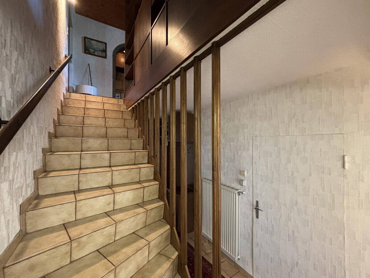 Geflieste Treppe mit Holzgeländer führt in die obere Etage des Hauses.