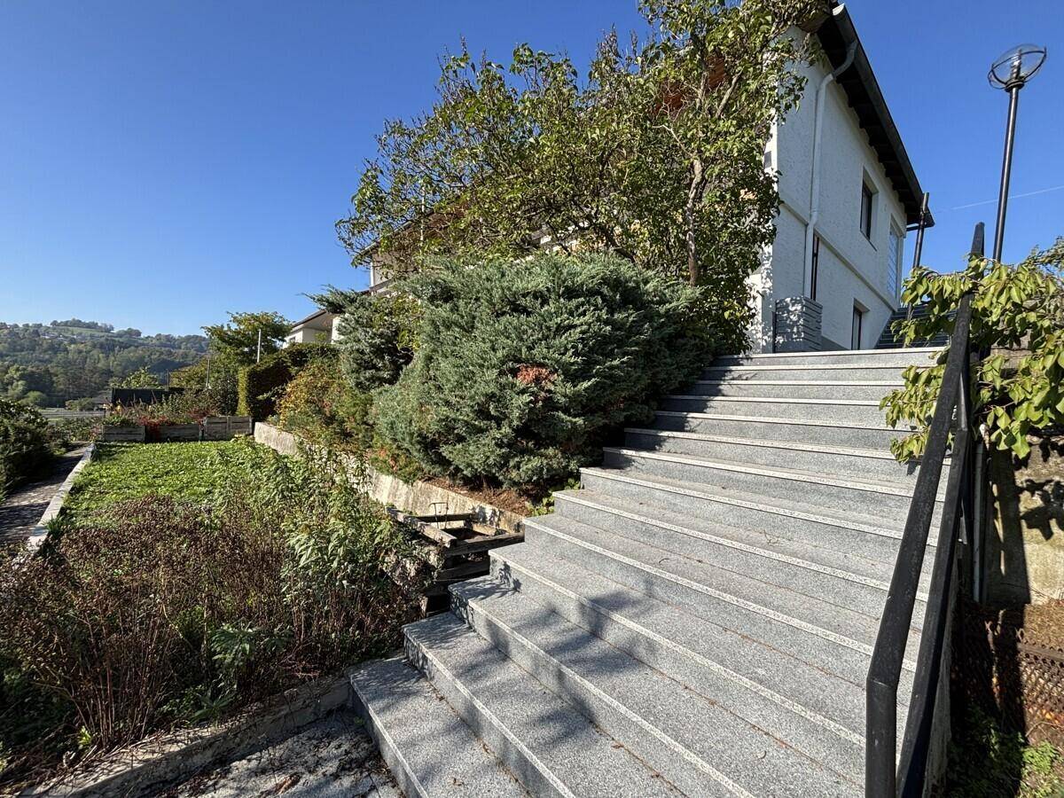 Steintreppe führt durch den terrassierten Gartenbereich mit üppiger Vegetation.