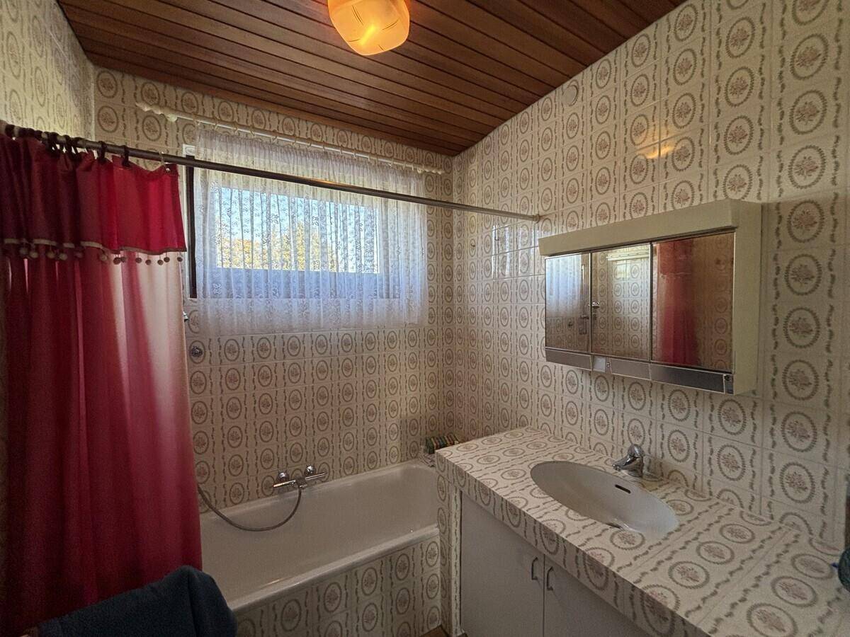 Badezimmer mit Badewanne, Waschbecken und gemusterten Fliesen im Retro-Stil.