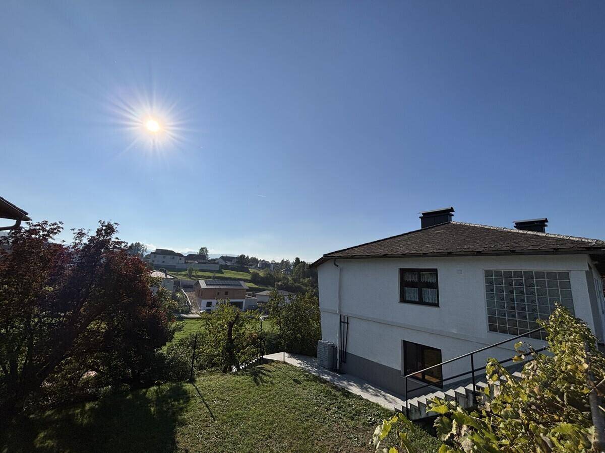 Weitläufiger Gartenbereich mit Rasen und Blick auf die sonnige Landschaft und das Haus.