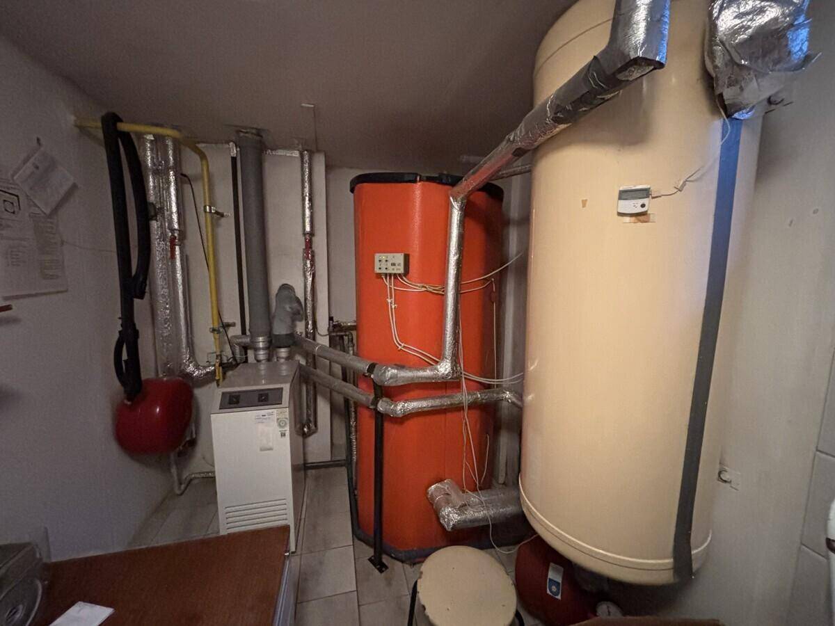 Heizungsraum mit großen Warmwasserspeichern und komplexen Rohrleitungen für die Gebäudetechnik.