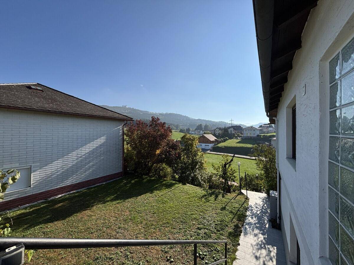 Sonnige Rasenfläche neben dem Haus mit Blick auf die umliegende Hügellandschaft.