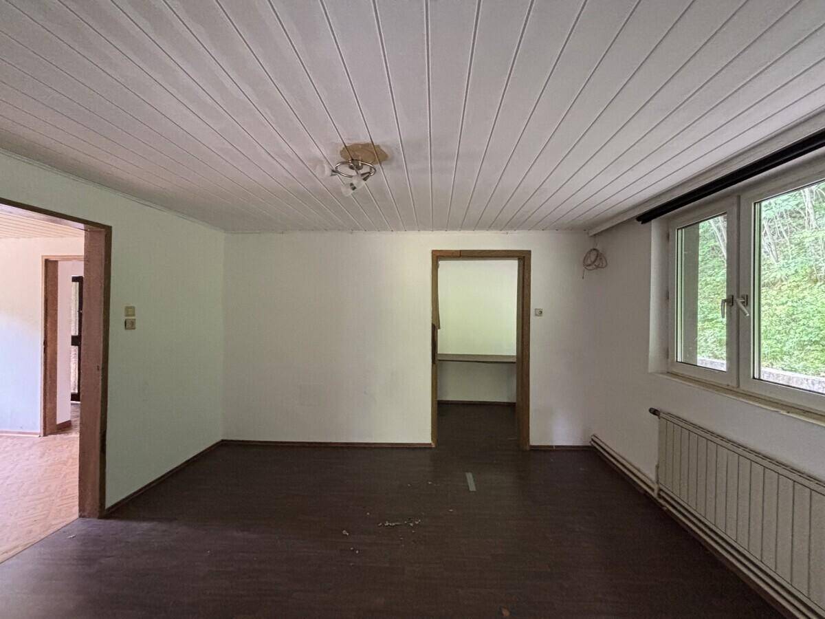 Helles Wohnzimmer mit Laminatboden, weißen Wänden und Holzdeckenverkleidung.