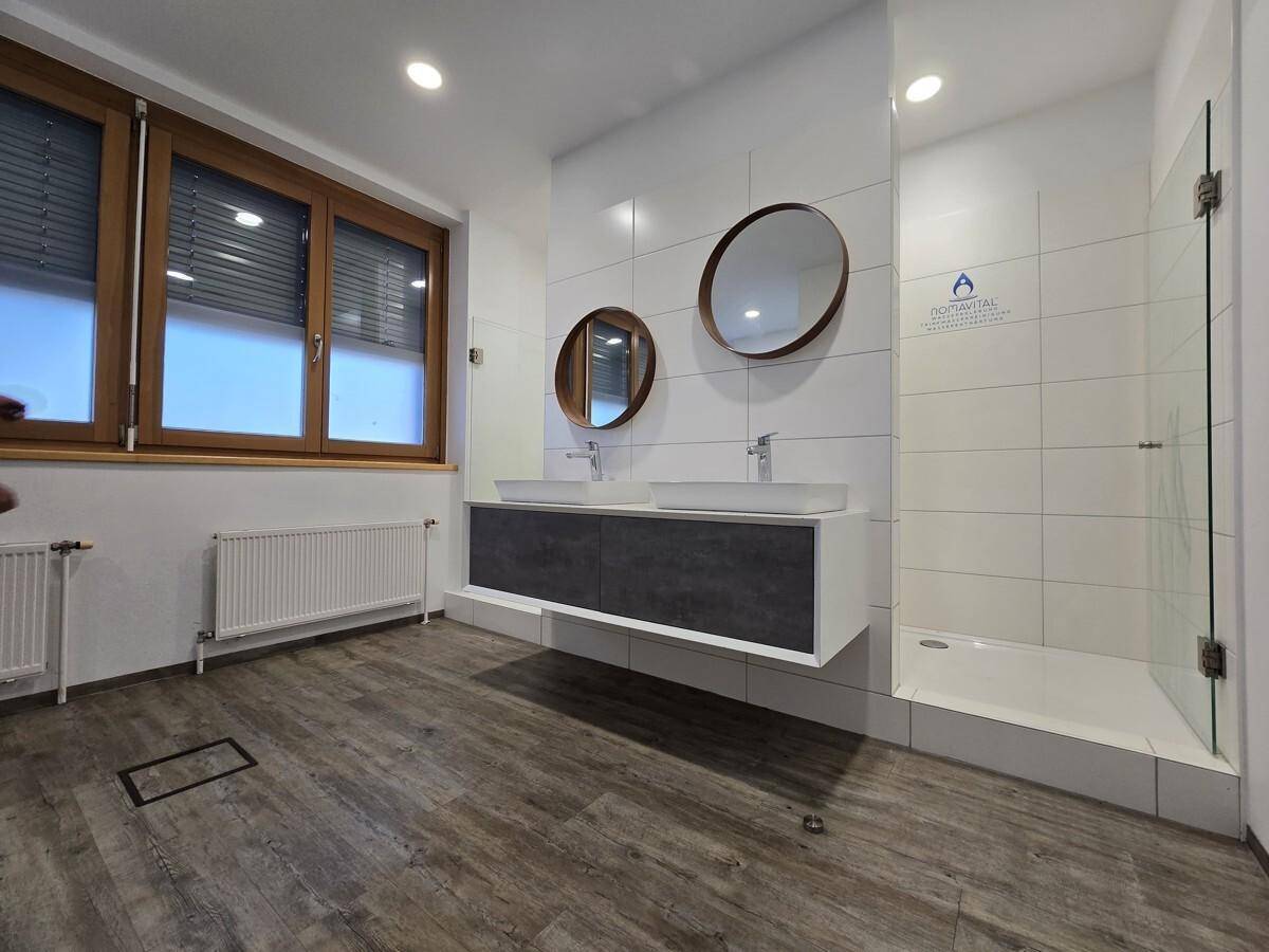 Helles, modernes Badezimmer mit Fenster, Doppelwaschbecken und einer geräumigen Duschkabine.