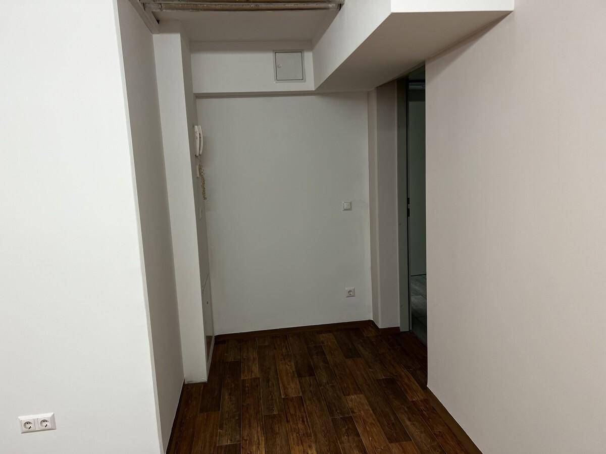 Heller Flurbereich mit dunklem Laminatboden und einer Gegensprechanlage an der weißen Wand.