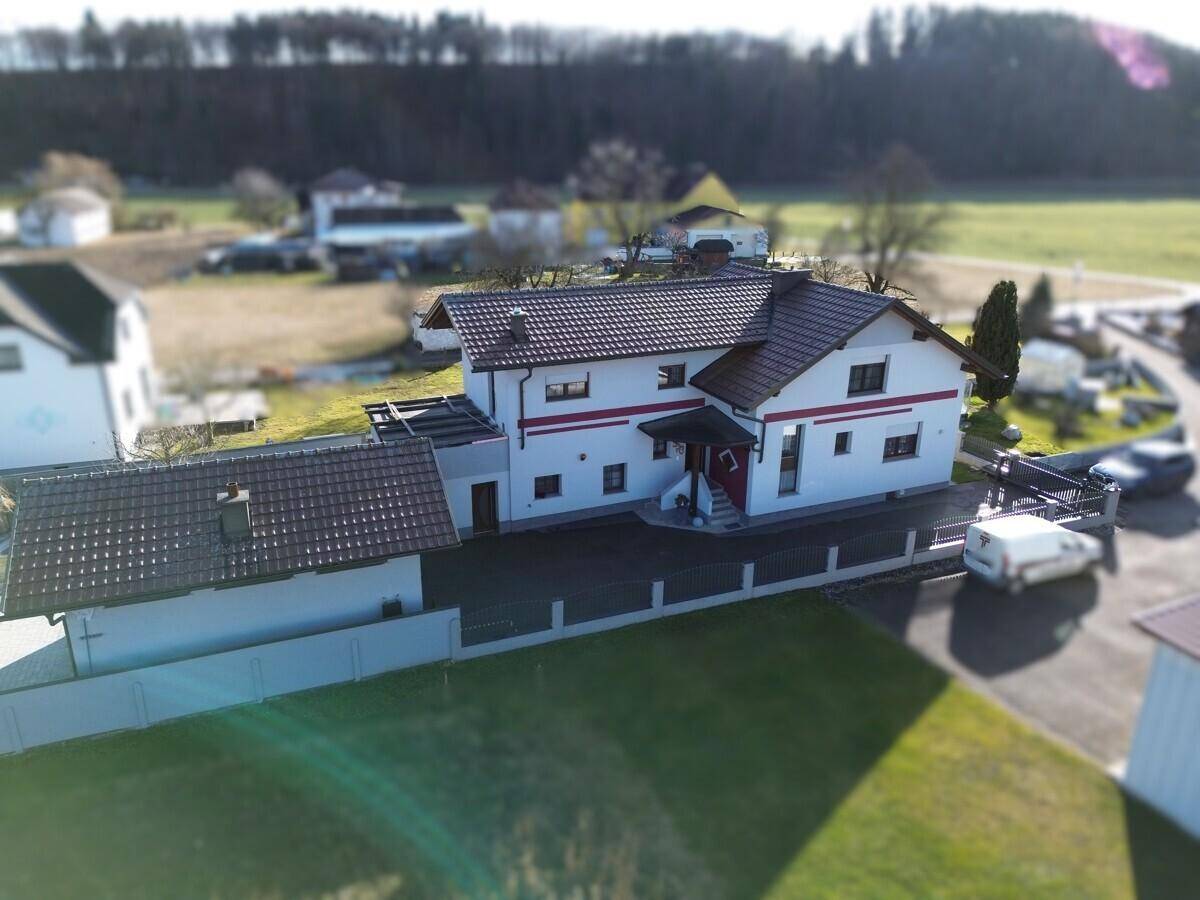 Weitläufige Luftaufnahme des Hauses mit Zufahrt, Garten und umliegender grüner Landschaft.