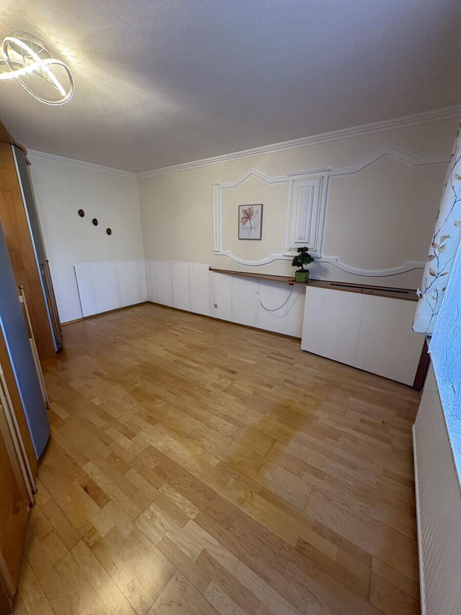 Helles Schlafzimmer mit Holzboden und dekorativer Wandverkleidung, bereit zur individuellen Gestaltung.