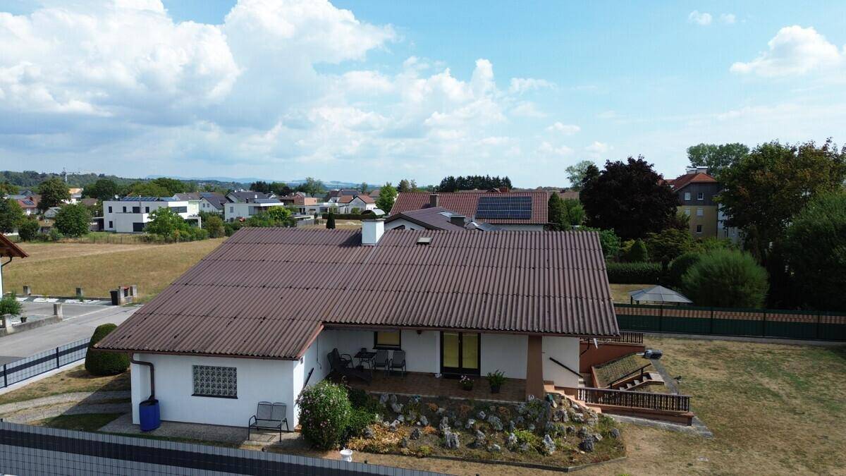 Luftaufnahme des Einfamilienhauses mit weitem Blick über die umliegende Landschaft und Nachbarschaft.