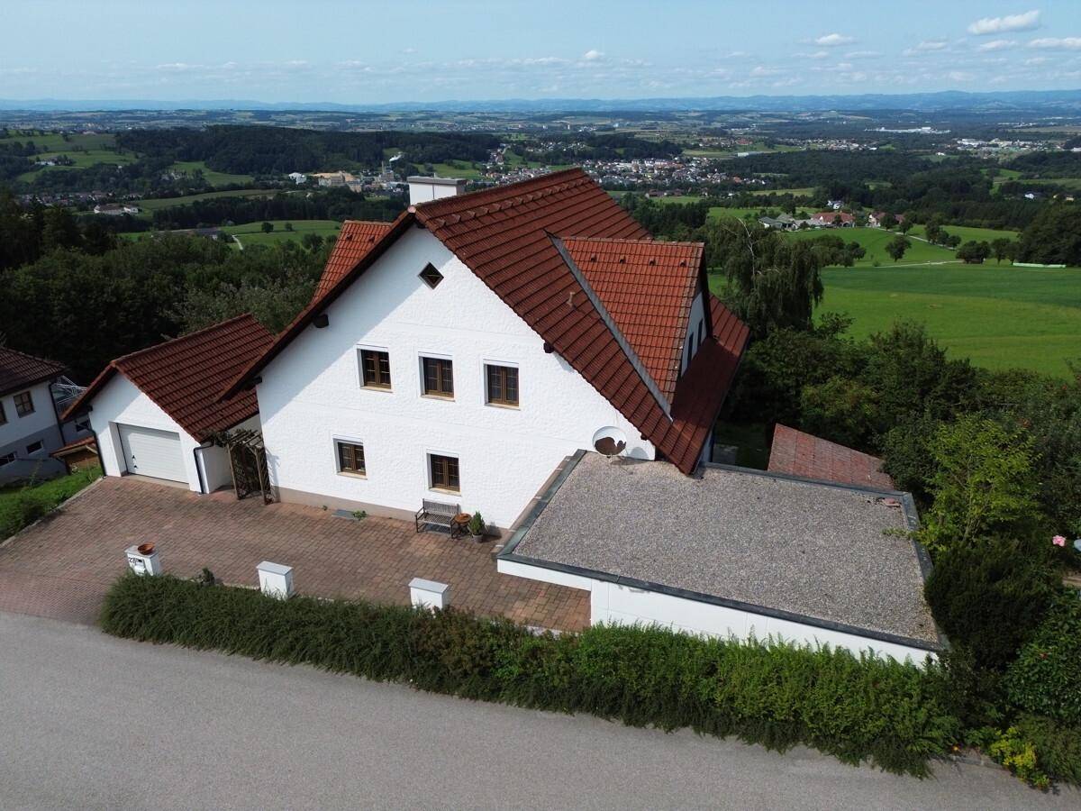 Weitläufige Luftaufnahme des Hauses mit weitem Blick über die grüne Landschaft und entfernte Ortschaften.