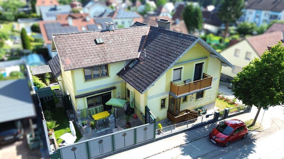Drohnenaufnahme eines Einfamilienhauses mit Garten, Terrasse und Balkon in einer Wohnsiedlung.