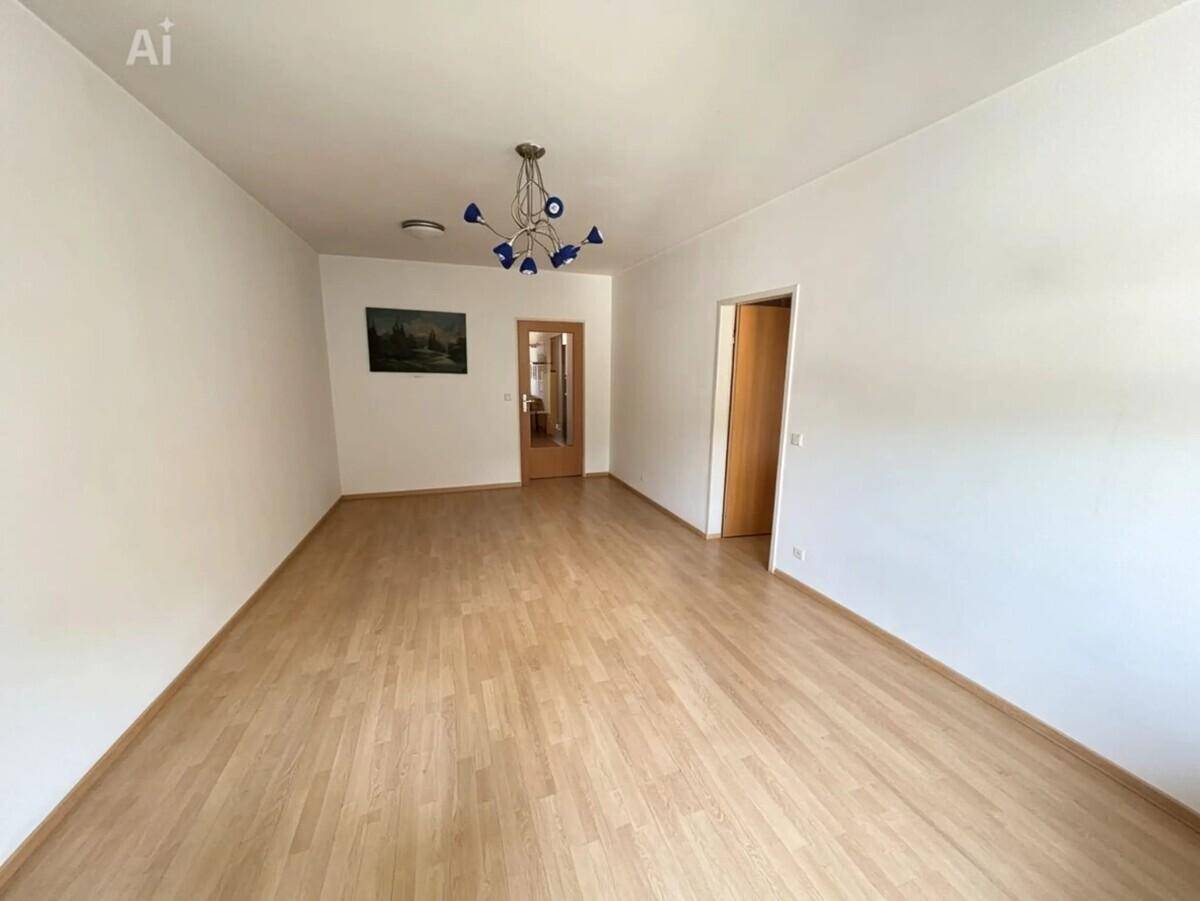 Geräumiges Wohnzimmer mit Laminatboden und weißen Wänden, bereit zur Einrichtung.