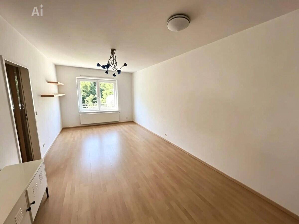 Heller Wohnbereich mit Laminatboden und weißen Wänden, bietet viel Tageslicht durch das Fenster.
