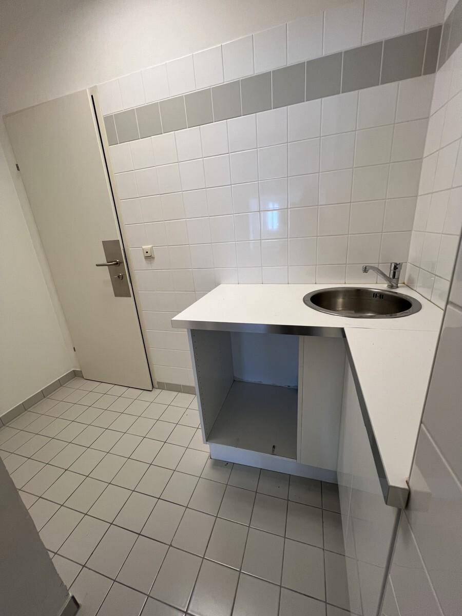Kleine Küchenzeile mit Edelstahlspülbecken, weißen Fliesen und einem praktischen Arbeitsbereich.