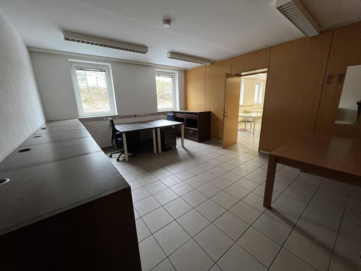 Großes Büro mit mehreren Arbeitsplätzen, Holzvertäfelung und Blick auf einen weiteren Raum.