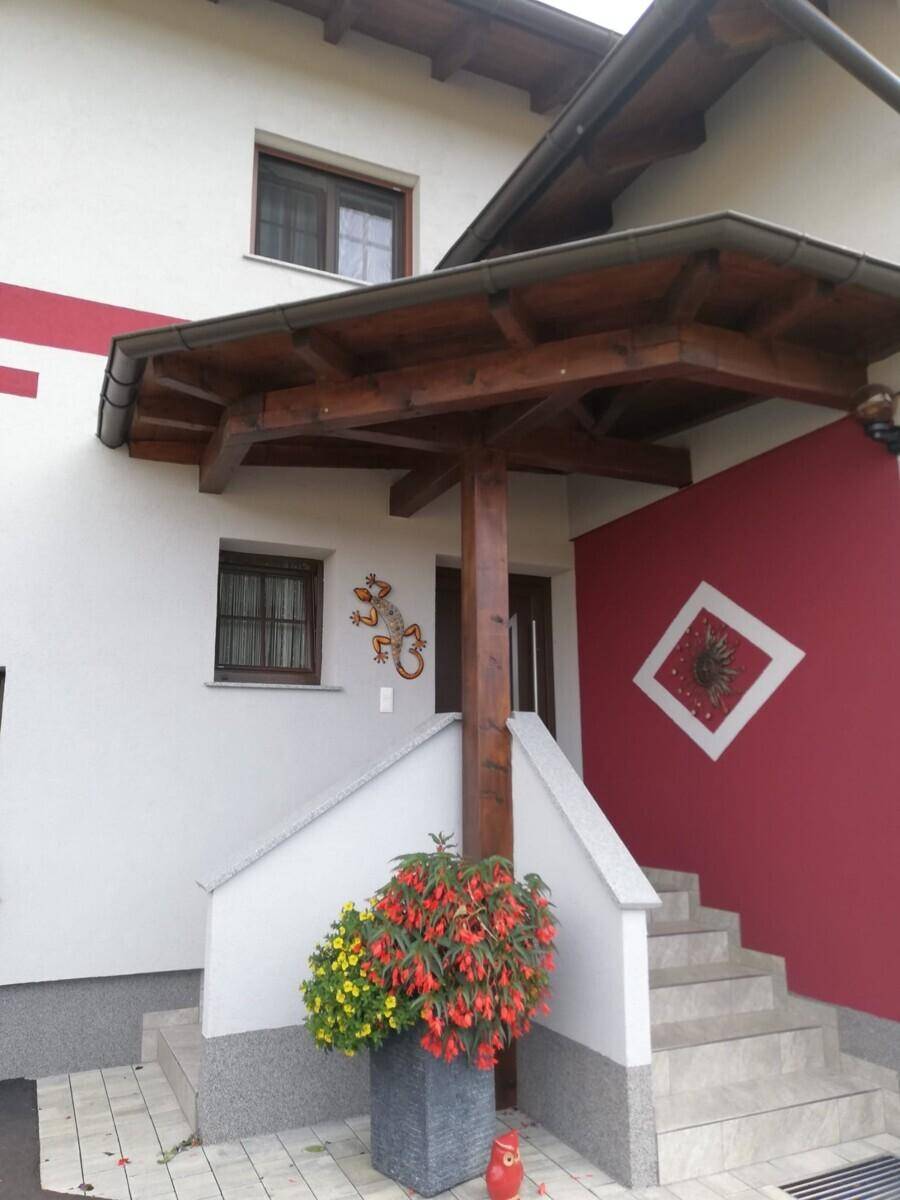Hauseingang mit überdachtem Vordach, Treppe und dekorativen Pflanzen.