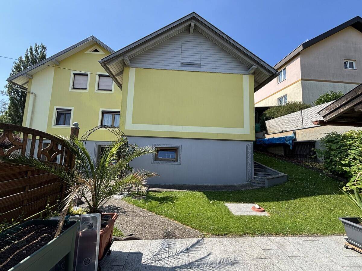 Seitenansicht des Hauses mit Rasenfläche und Treppe zum unteren Bereich.